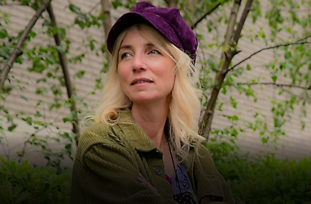 Instructional designer for course design consultancy sits in park wearing a purple hat